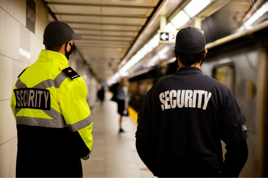 Zwei Sicherheitskräfte mit Security-Aufschrift auf einem U-Bahnsteig